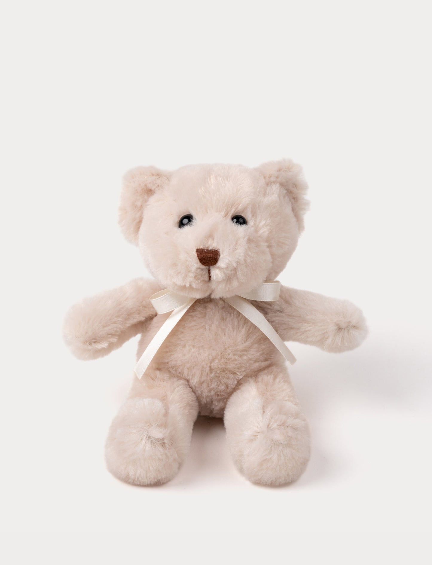 A teddy bear with warm beige fur, an embroidered nose, and an adorable satin bow.