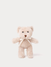 A teddy bear with beige fur, an embroidered nose, and an adorable satin bow.