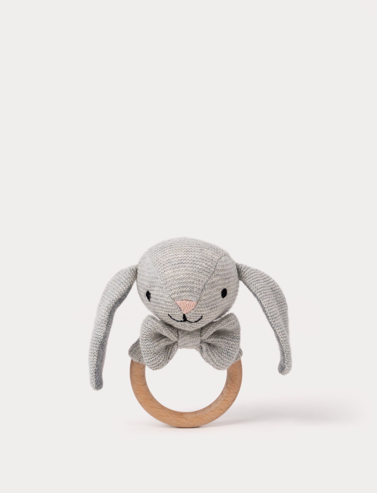  Image of Knitted grey bunny teething ring with floppy ears, embroidered facial features, a bow, and a smooth wooden handle.