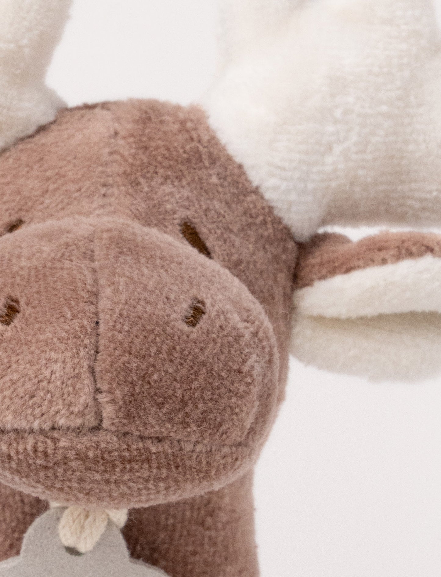 A plush moose rattle with a soft brown body, white antlers, and a stitched face