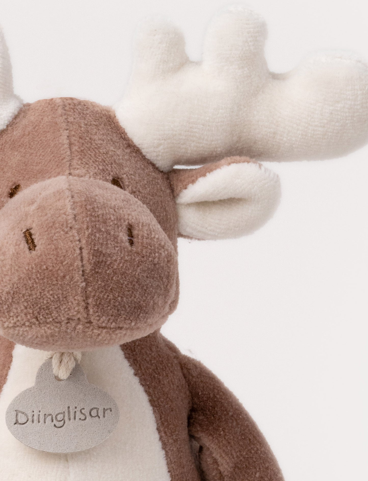 A soft brown plush moose, with white antlers, a stitched face and white and brown details.