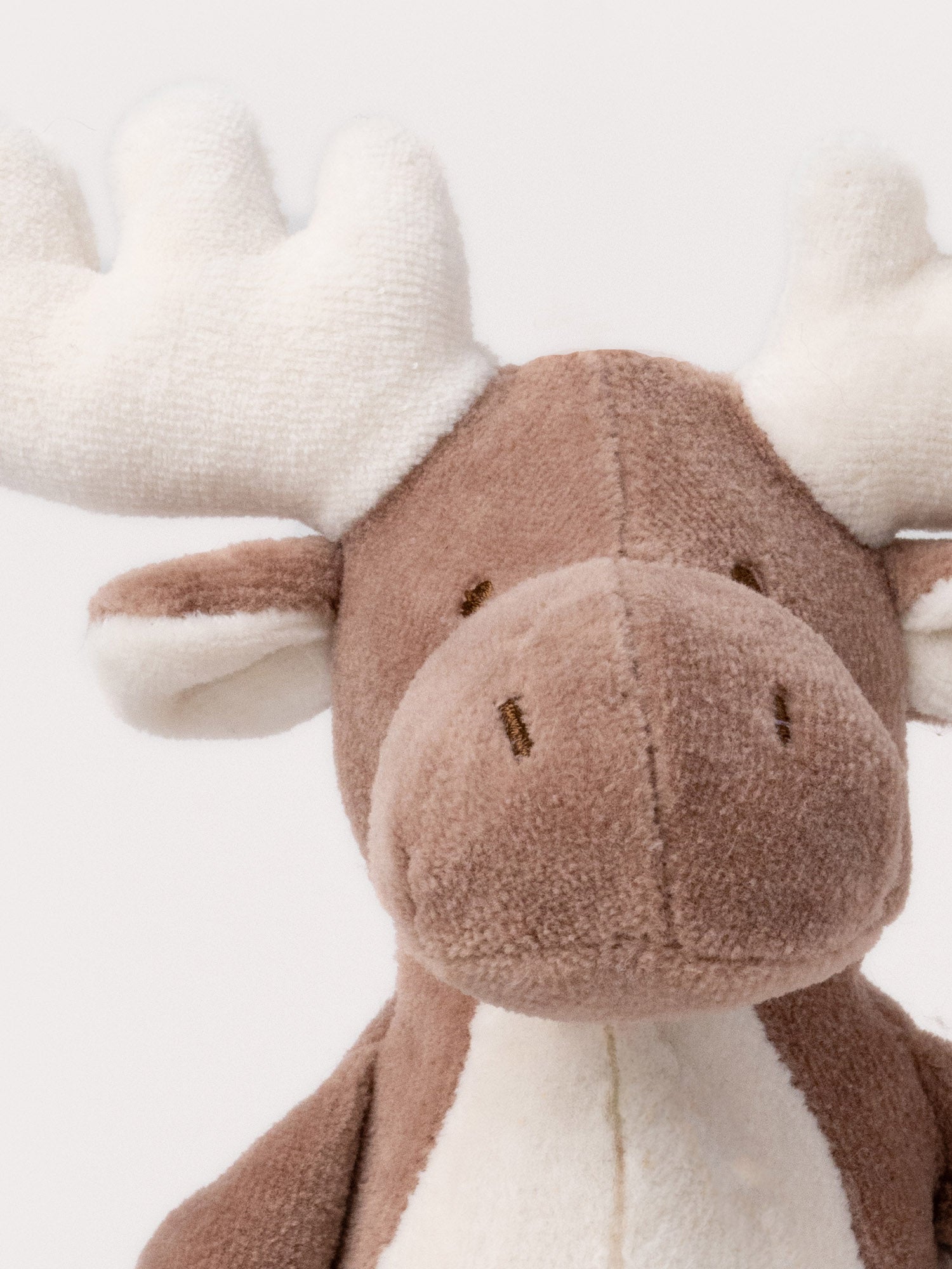  Image of A soft brown plush moose, with white antlers, a stitched face and white and brown details.