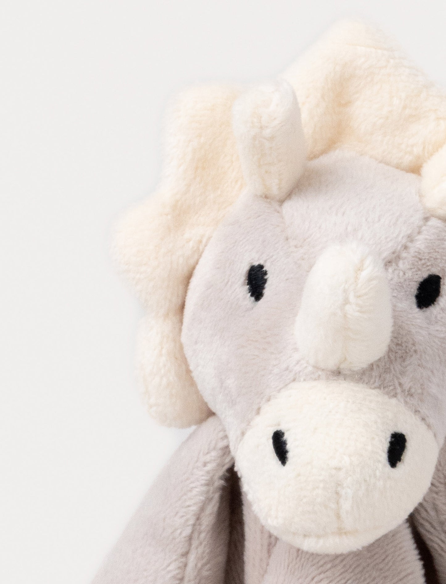 Soft baby blanket with a plush gray dino head, white spikes, and cream-trimmed edges.