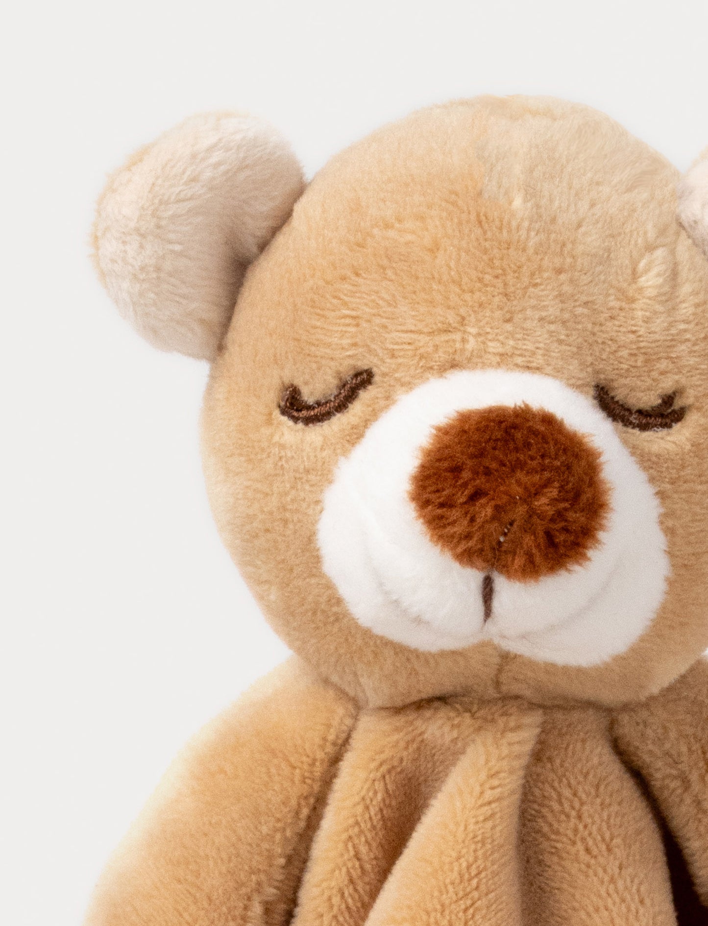 Soft baby blanket with a plush brown bear head, closed eyes, and cream-trimmed edges.