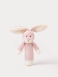 Soft plush bunny rattle with a light pink body, long floppy ears, embroidered eyes, and white accents on the hands and base.