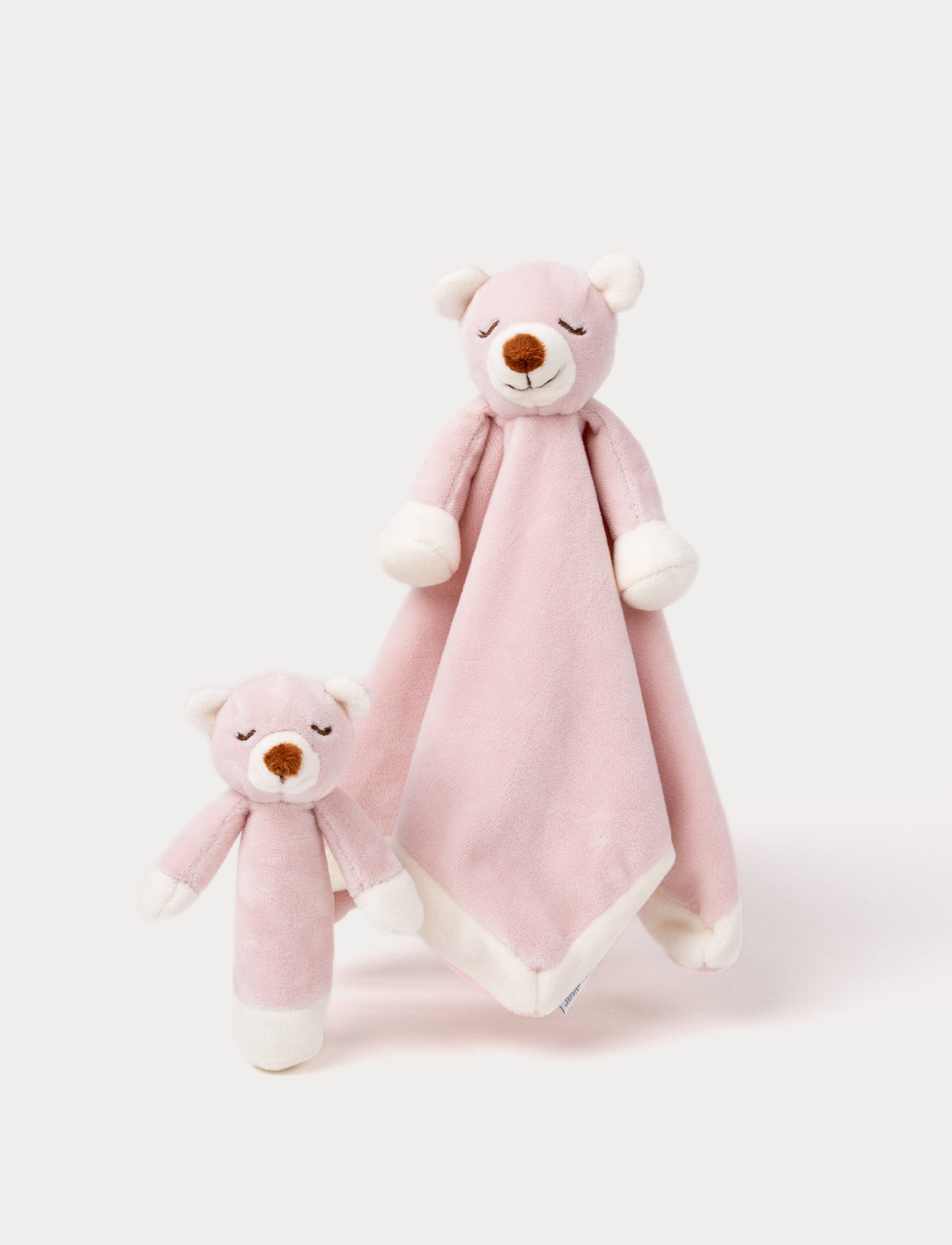 Soft pink bear plush set with white accents, featuring a cuddle blanket and matching rattle toy with closed eyes.