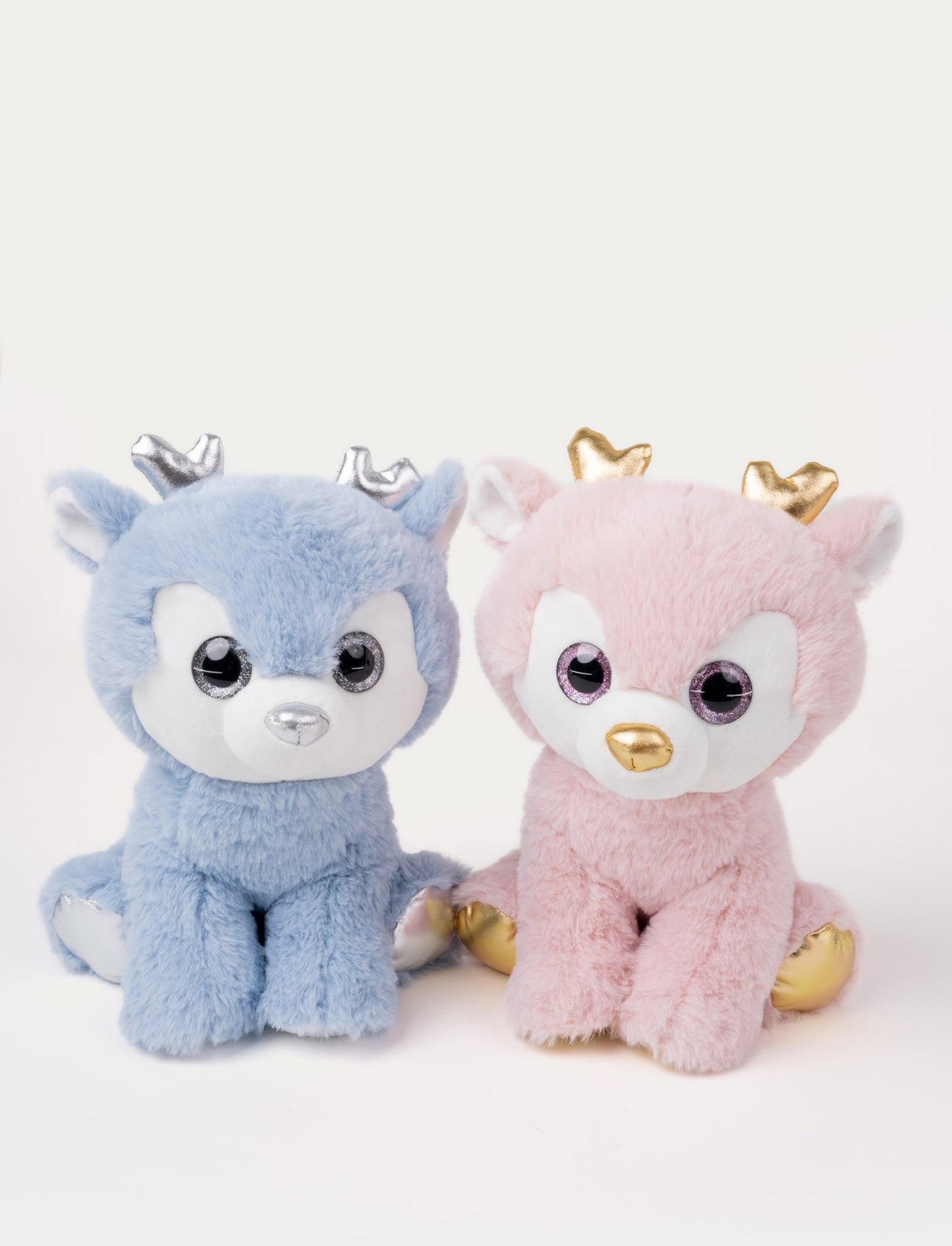 Two plush deer, one blue with silver accents and one pink with gold accents, sitting side by side.