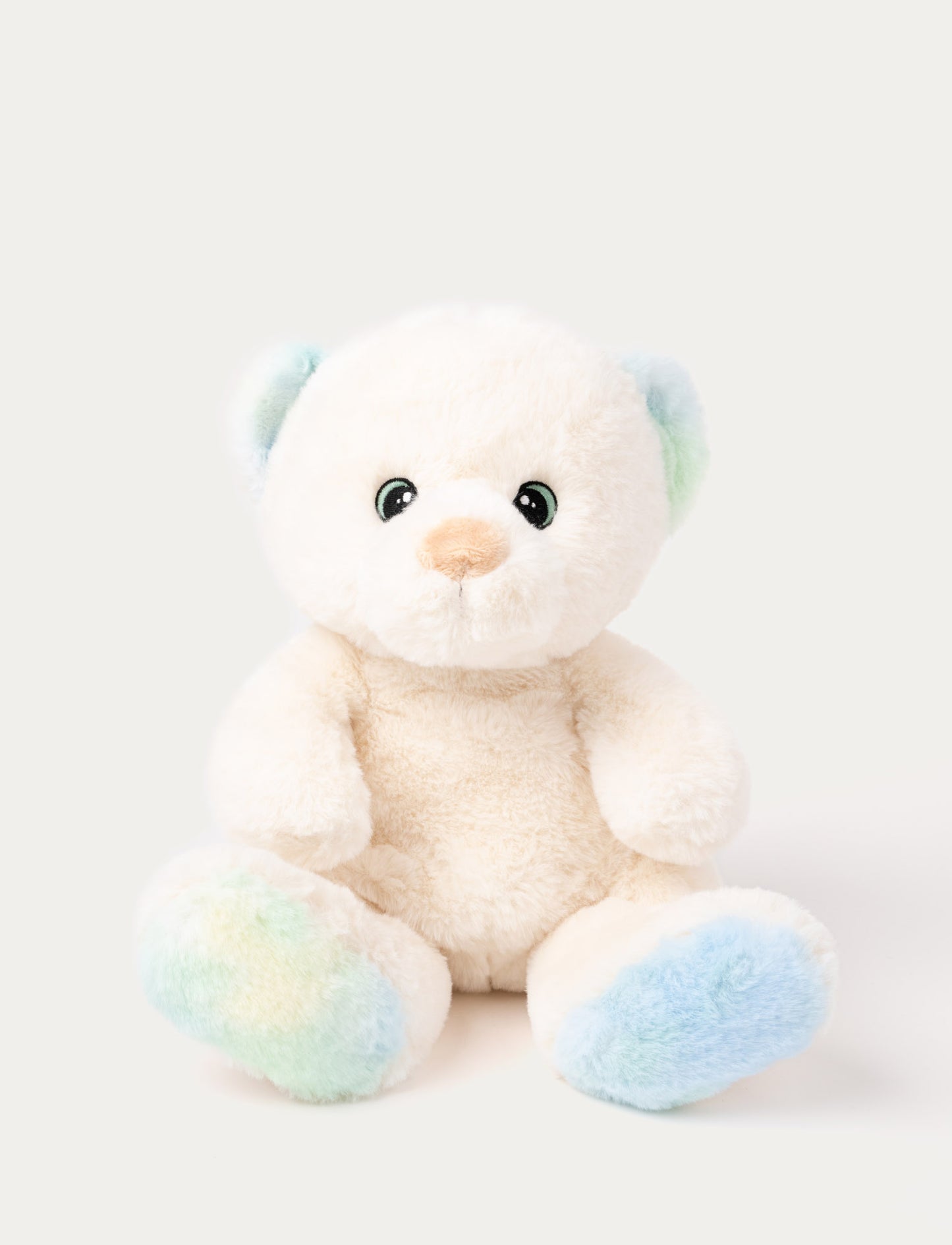 A teddy bear with cream-colored fur and pastel details on his ears and feet, with embroidered eyes.