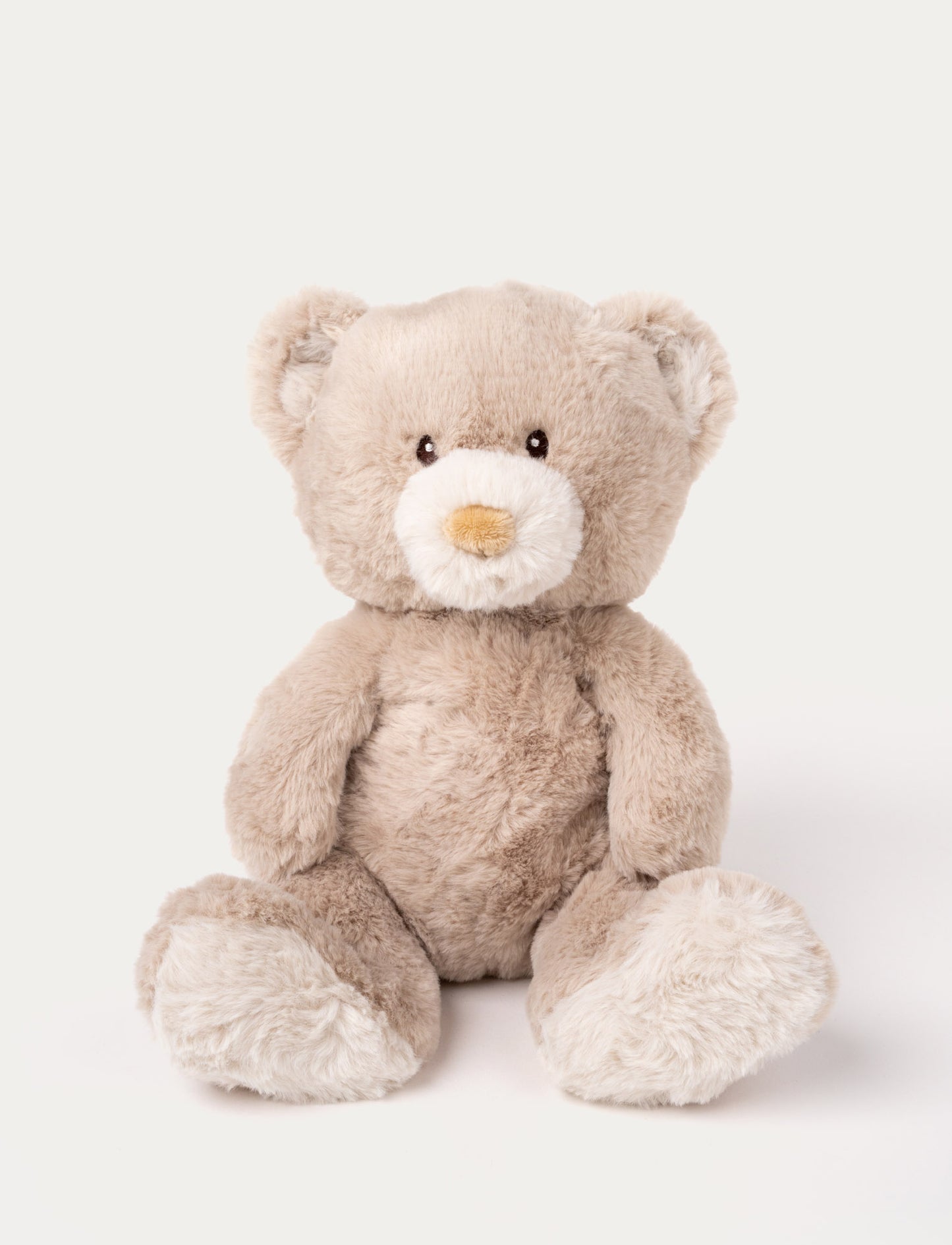 A beige teddy bear with soft fur, faux suede detail on its back, and embroidered eyes.