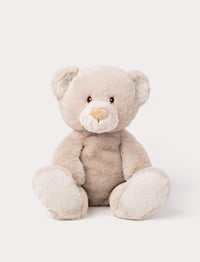 A beige teddy bear with soft fur, faux suede detail on its back, and embroidered eyes.