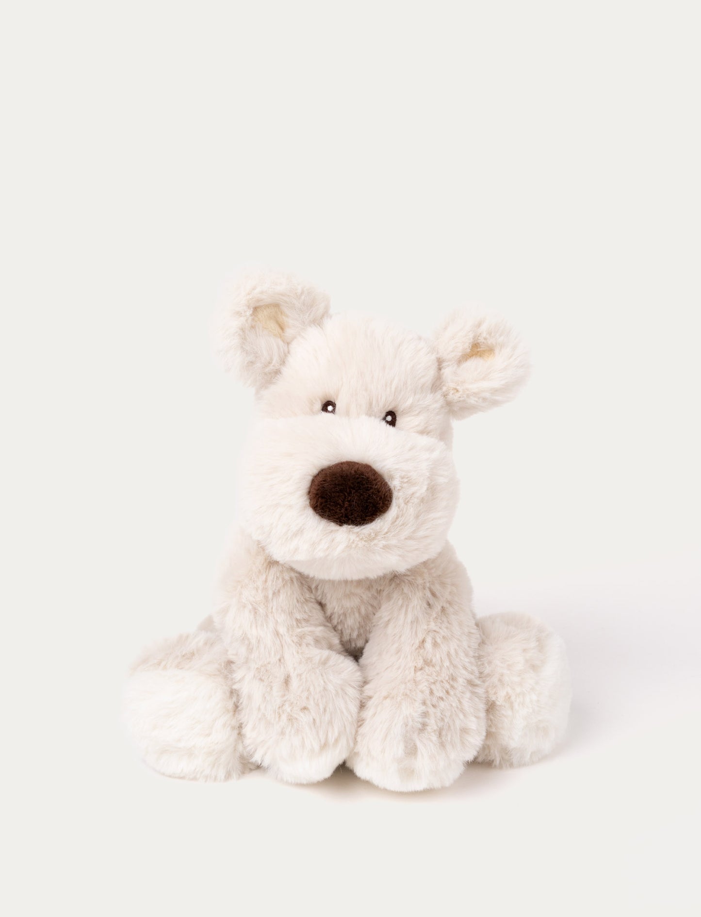 A beige plush dog with soft fur, faux suede detail on its back, and embroidered eyes.