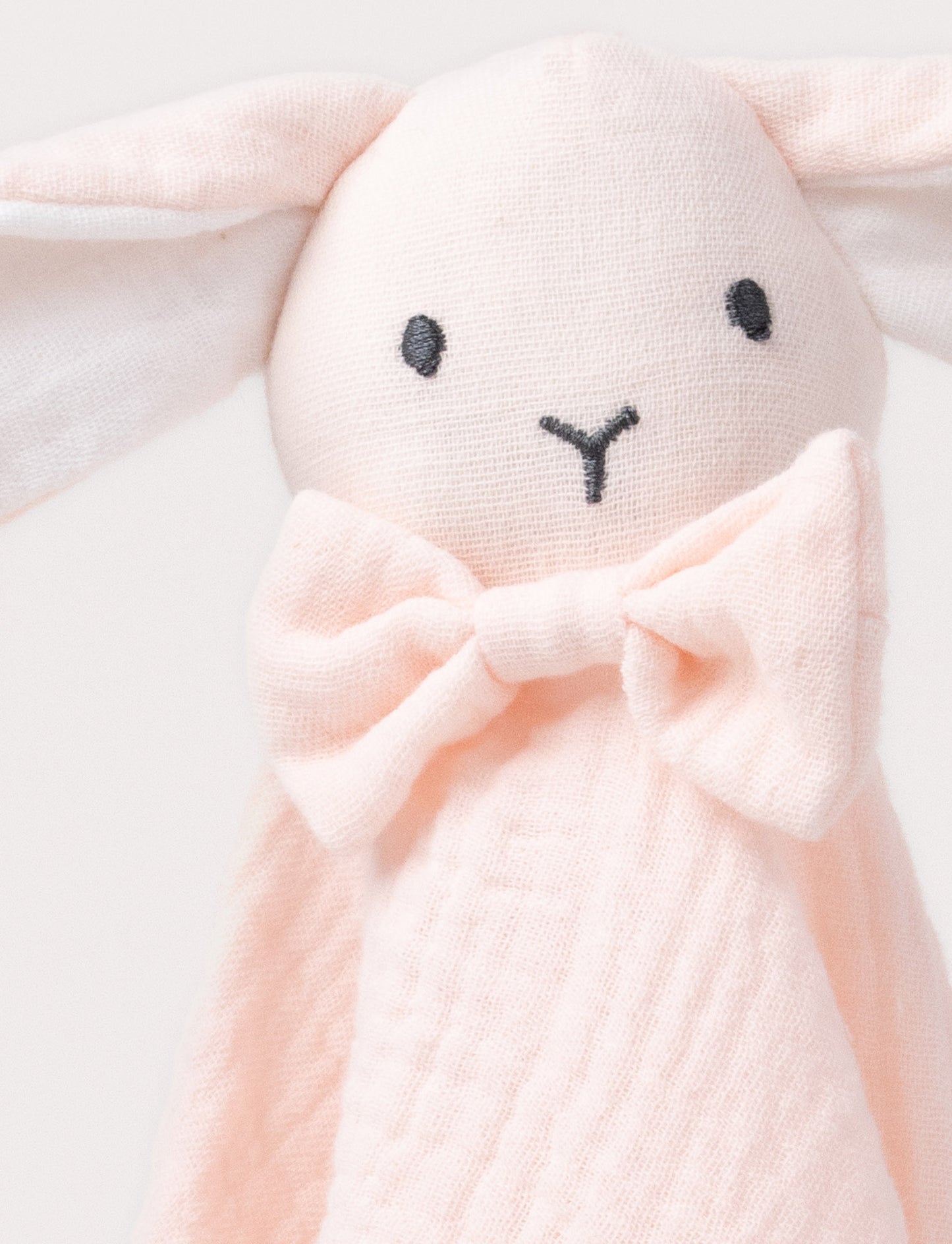 Soft baby blanket with a plush pink bunny head, long floppy ears, and a small bow.