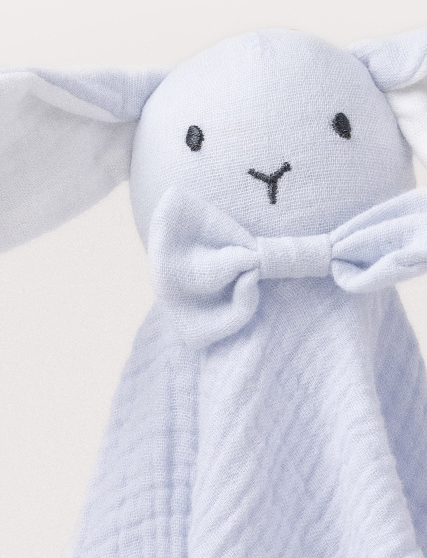 Soft baby blanket with a plush light blue , levander, bunny head, long floppy ears, and a small bow.