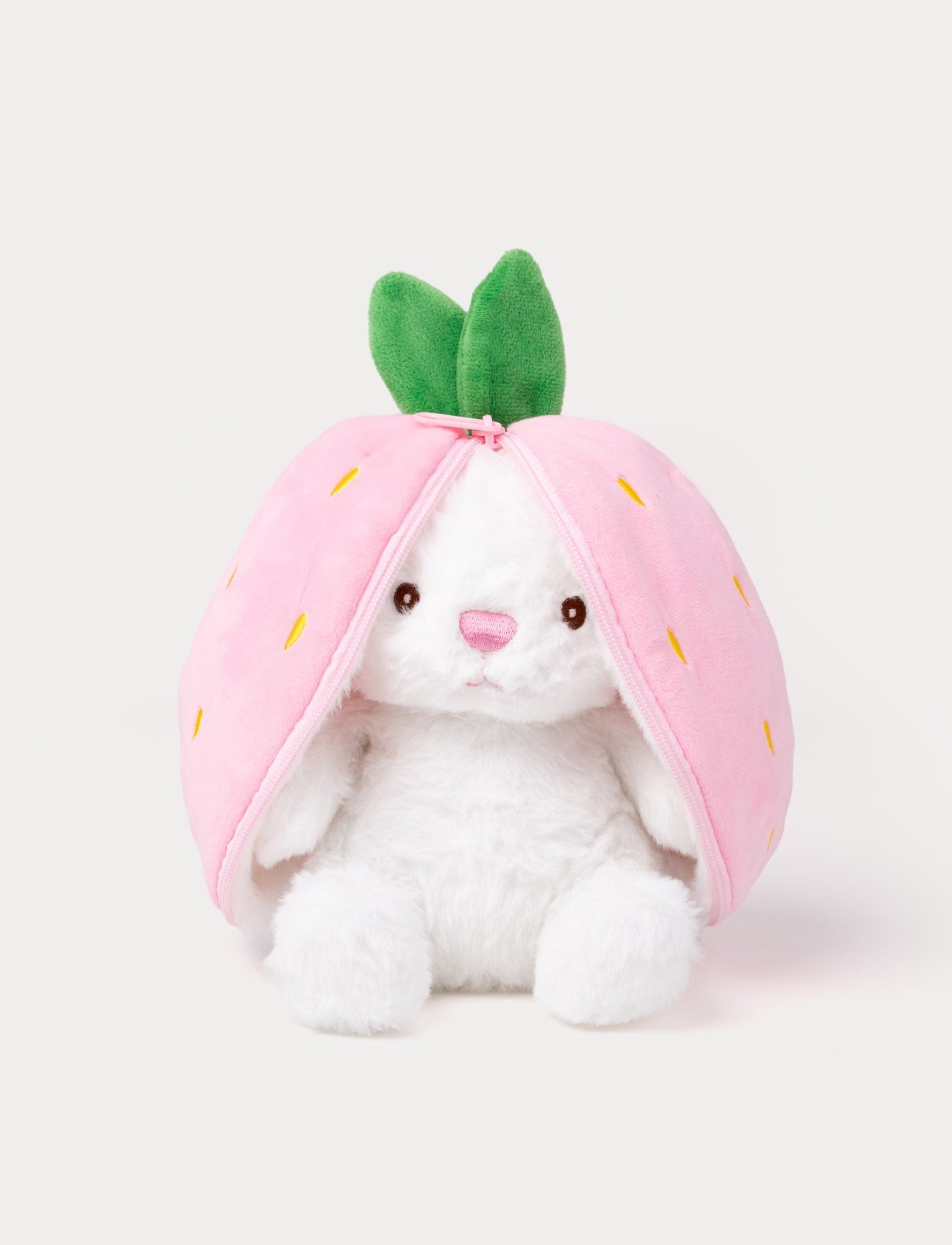  Image of White plush bunny sitting inside a pink strawberry pouch with zipper and green leaves on top.