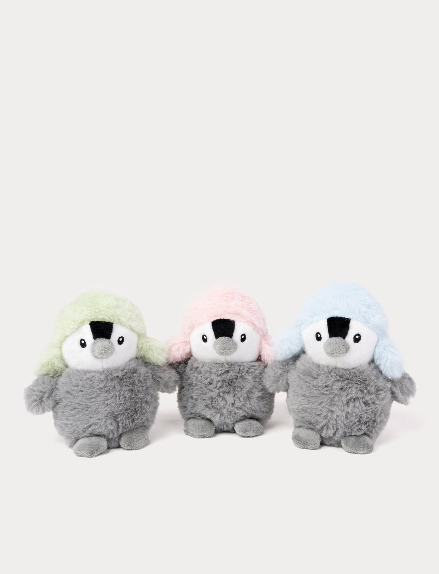 Three plush penguins with colorful hats on a white background