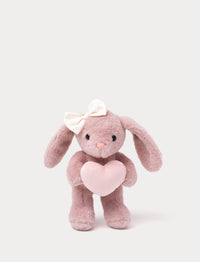 Soft pink bunny plush toy with white bow holding a pink heart.