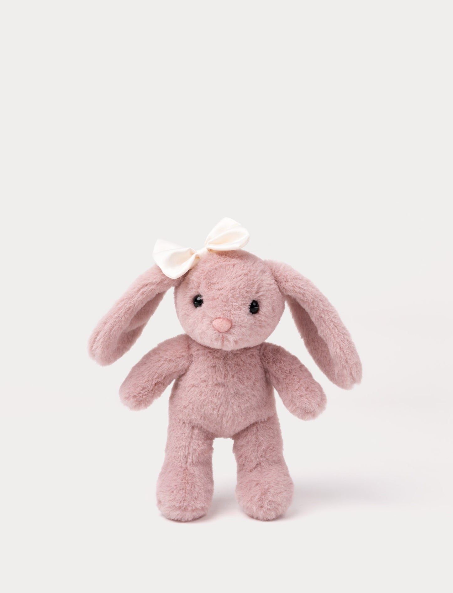 Soft pink bunny plush toy with long ears and white bow on its head.