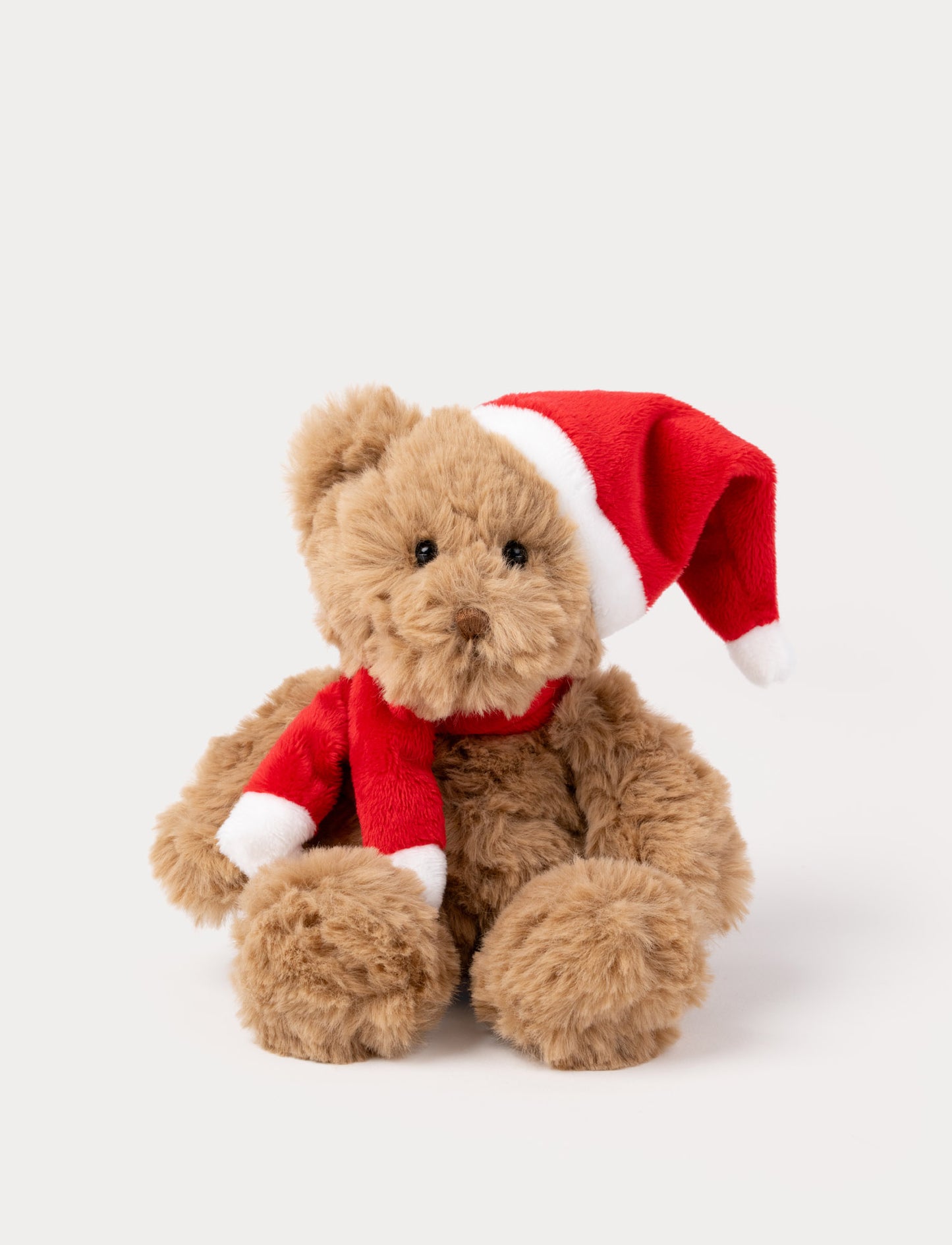 Soft brown teddy bear plush toy wearing a red Santa hat and scarf.
