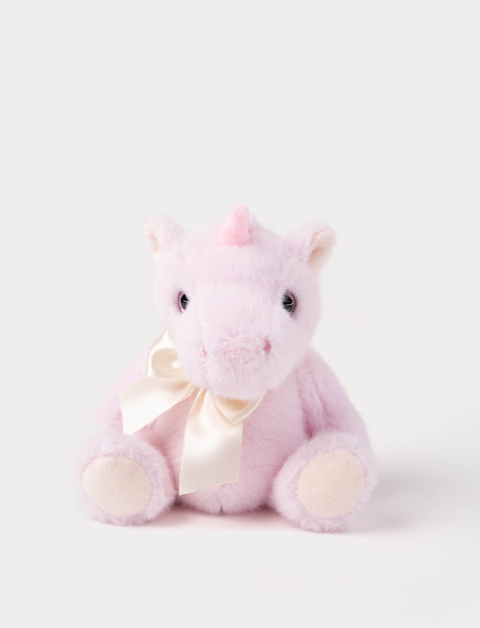  Image of Pink plush unicorn toy with a satin bow on a white background