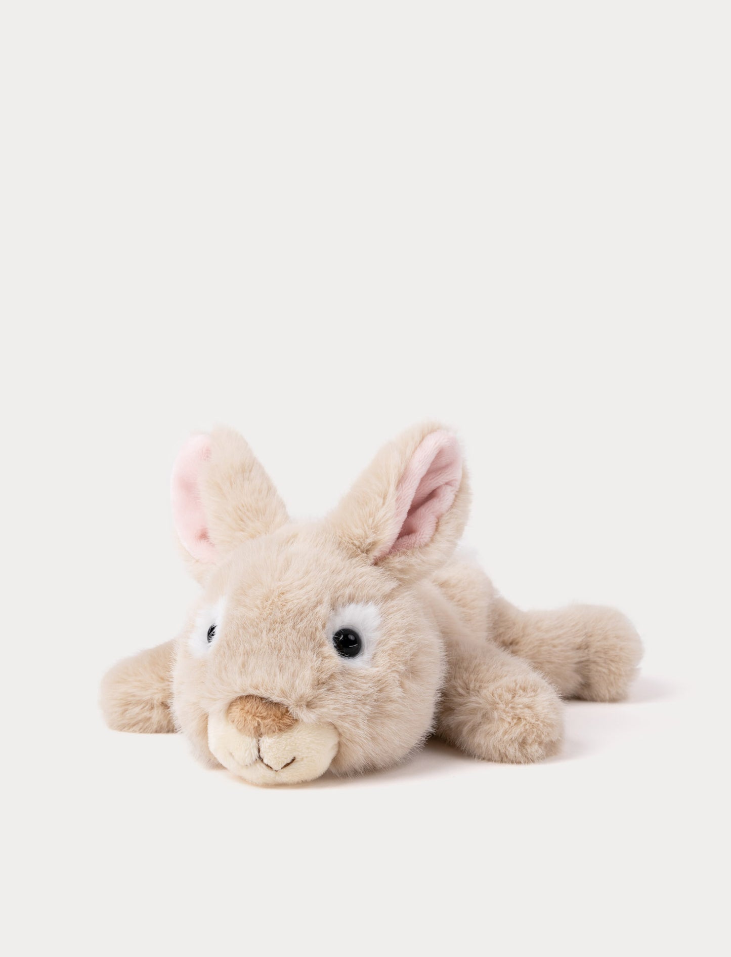 Plush beige toy bunny lying down