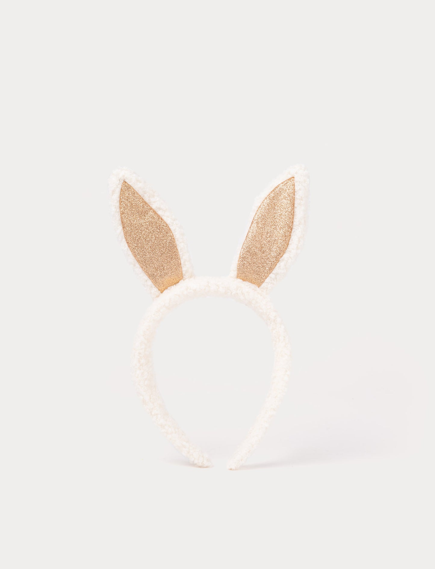 White headband with gold bunny ears on a light beige background