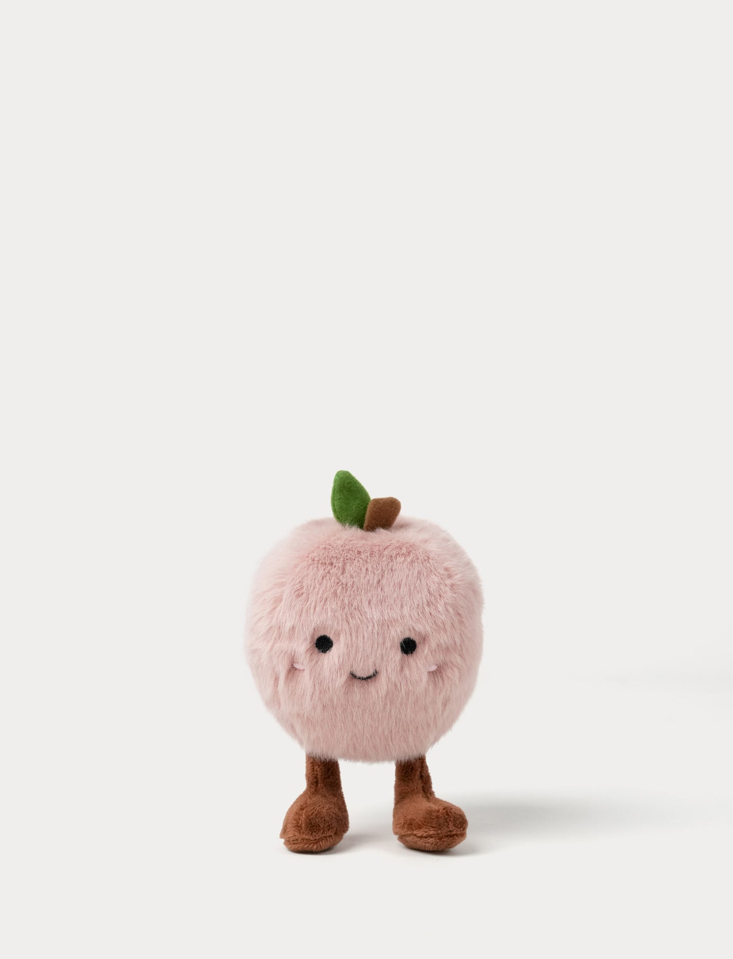 Plush toy shaped like a pink apple with a smiling face, cute legs and a green leaf 