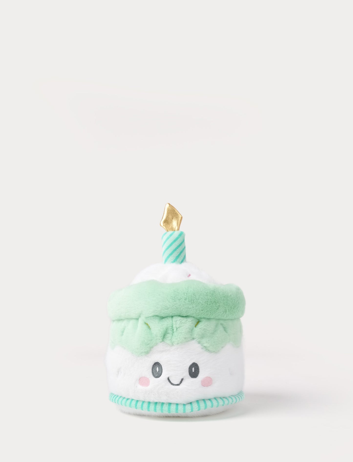 Plush toy resembling a birthday cake with a smiling face on a white background