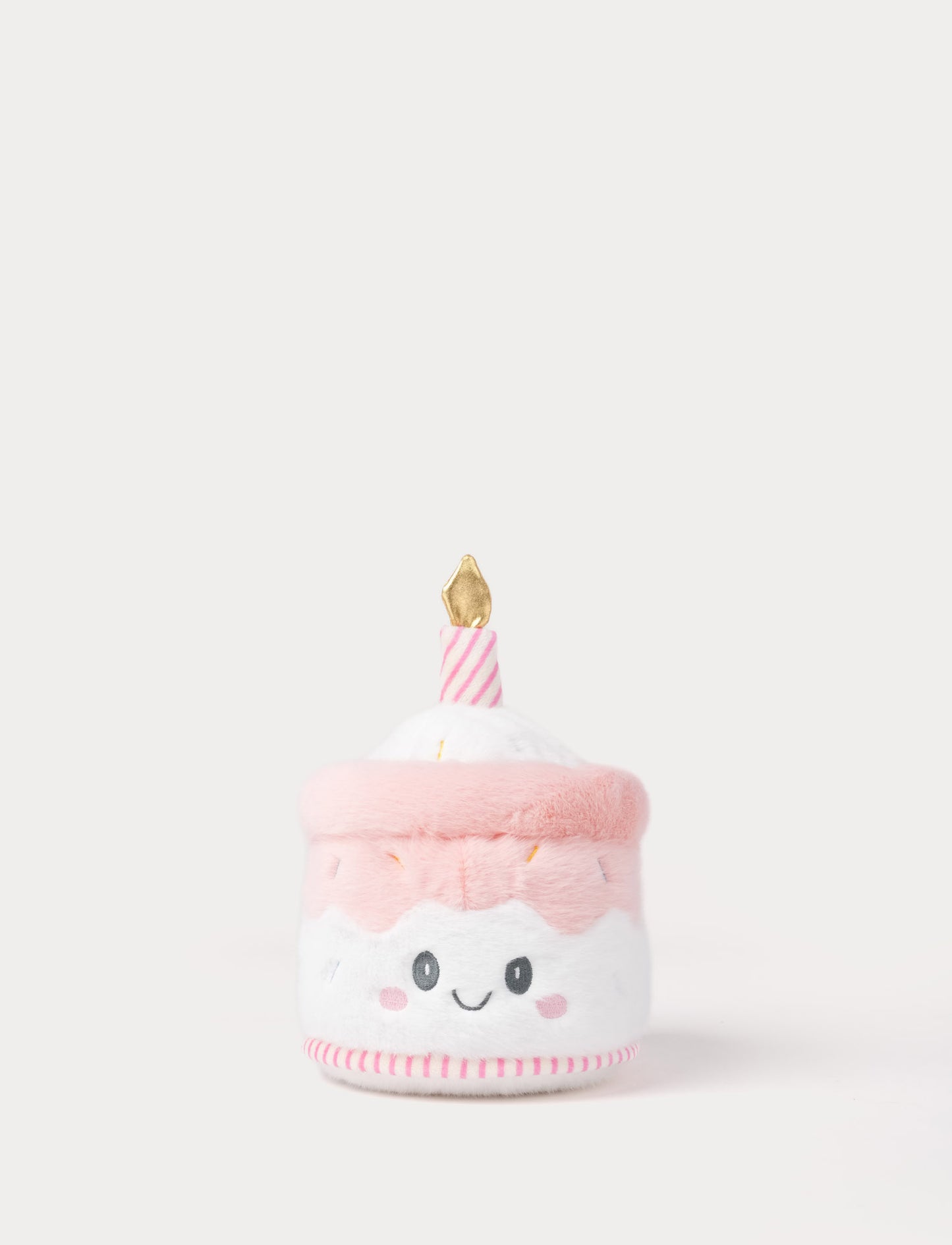 Pink plush toy resembling a birthday cake with a candle on a white background