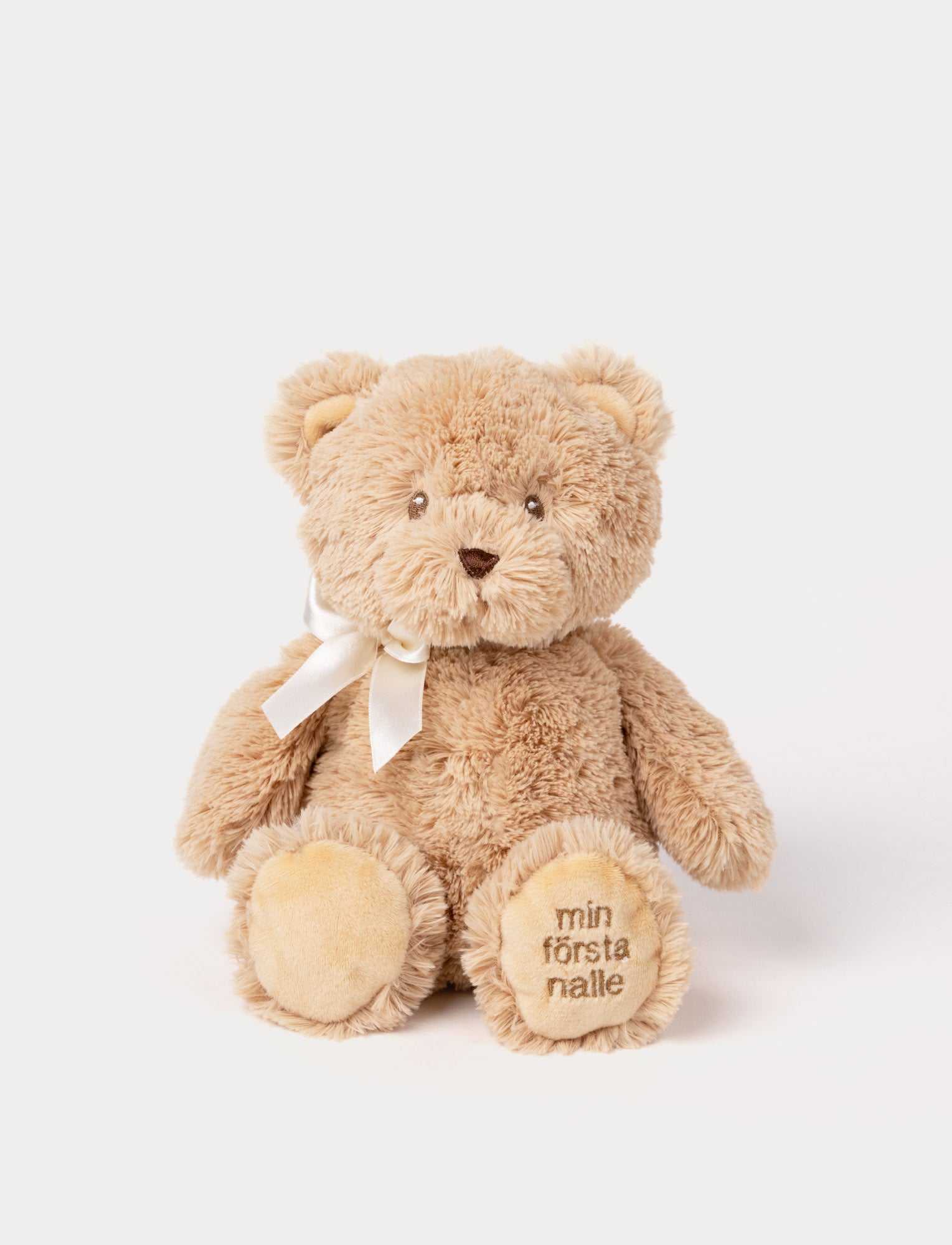  Image of Soft beige teddy bear plush with a white ribbon and "min första nalle" embroidered on the paw.